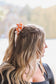 Woman wearing an orange cowboy scene scrunchie in her ponytail