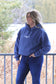 Woman looking to the side, standing outdoors in the Original Logo Hoodie (denim blue), showing the relaxed, cozy fit.