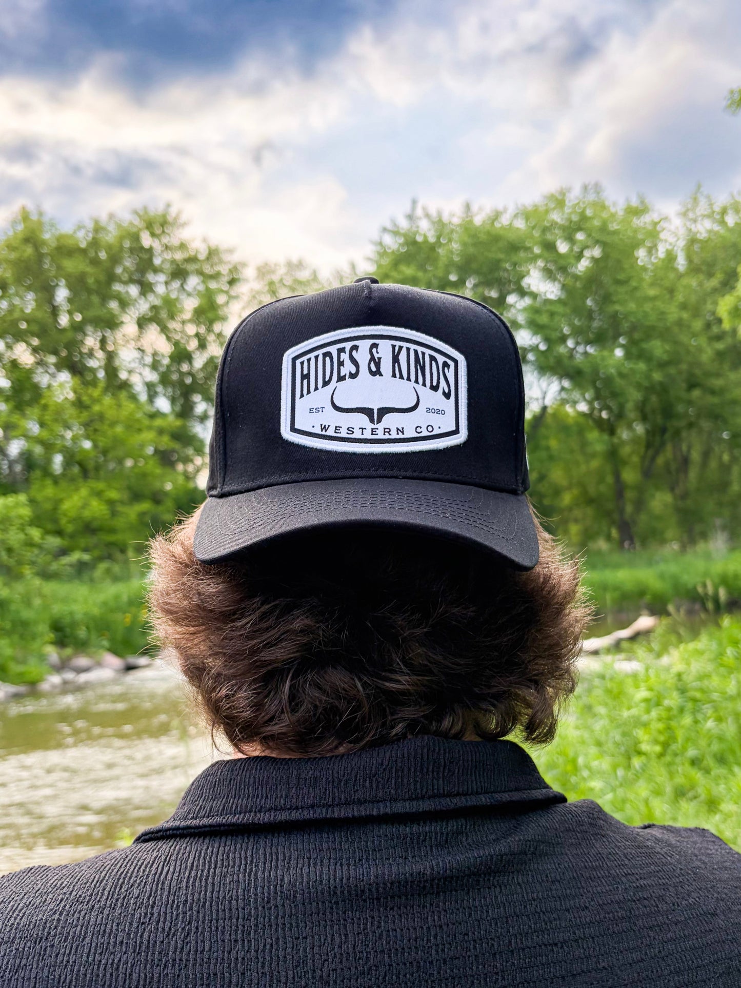 Model wearing the Hides & Kinds Outlaw Hat featuring an all black design and Western Co. patch.