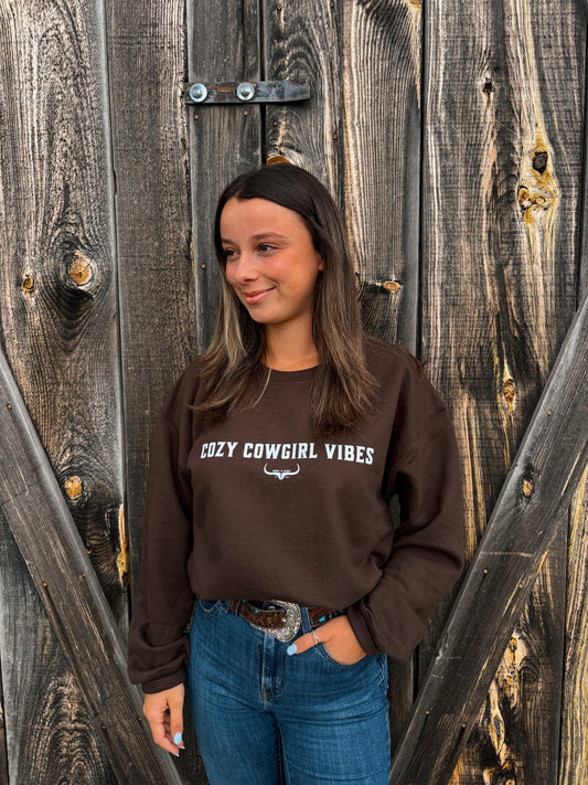 Model smiling while wearing the Cozy Cowgirl Vibes Crewneck from Hides & Kinds in chocolate brown