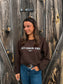 Model smiling while wearing the Cozy Cowgirl Vibes Crewneck from Hides & Kinds in chocolate brown