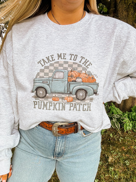 Woman wearing a grey crewneck sweatshirt with a vintage teal truck and pumpkins, reads "Take Me to the Pumpkin Patch" – cozy fall style by Hides & Kinds