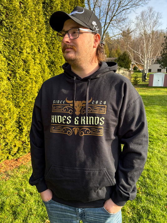 Lifestyle photo of men’s black Ranchline hoodie featuring gold Hides & Kinds western design