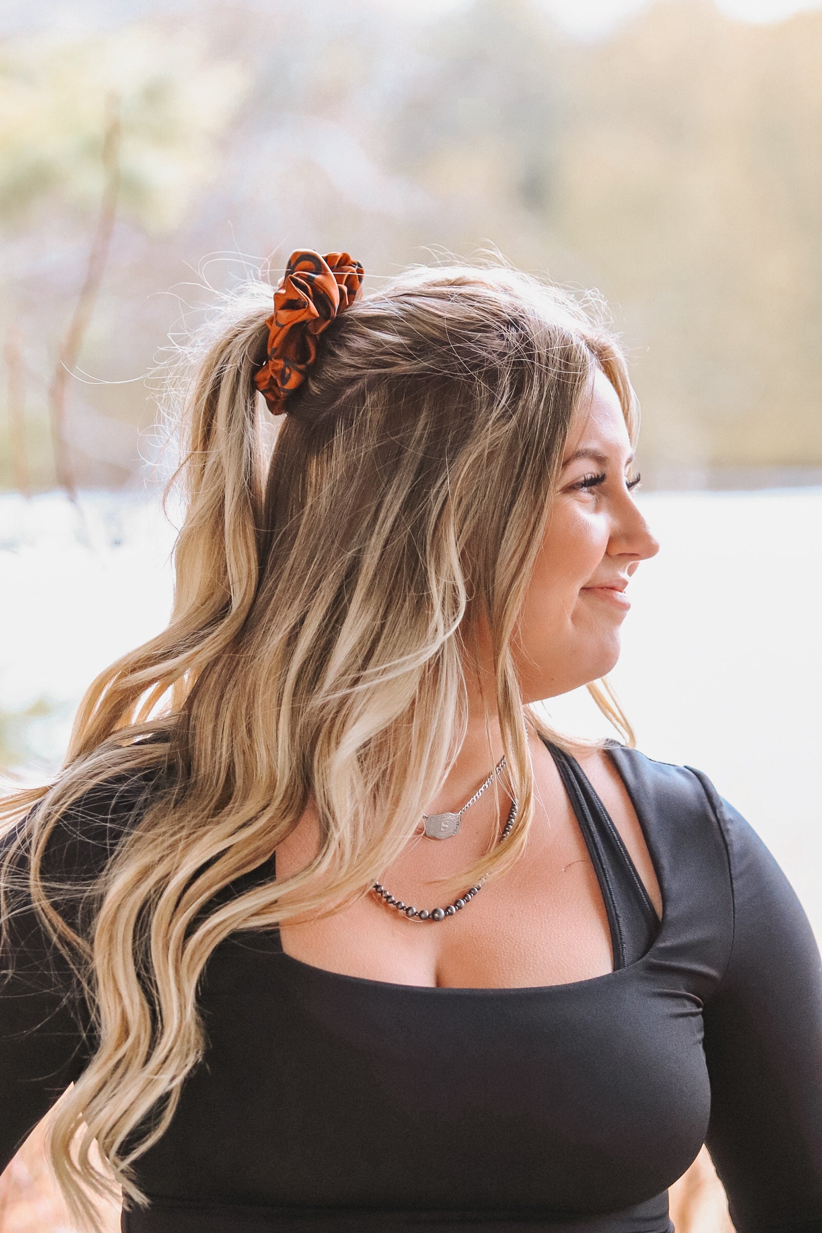 Woman wearing rust cattle brands scrunchie in ponytail – western hair accessory