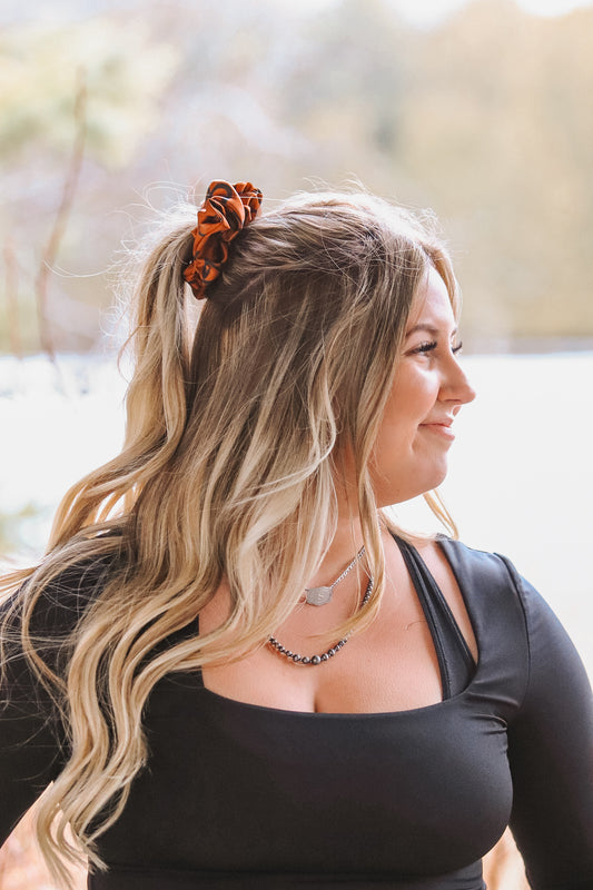 Woman wearing rust cattle brands scrunchie in ponytail – western hair accessory