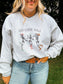 Close up of Skeleton Boot Scootin' Crewneck with three dancing skeletons in cowboy hats and boots, worn with light wash denim.
