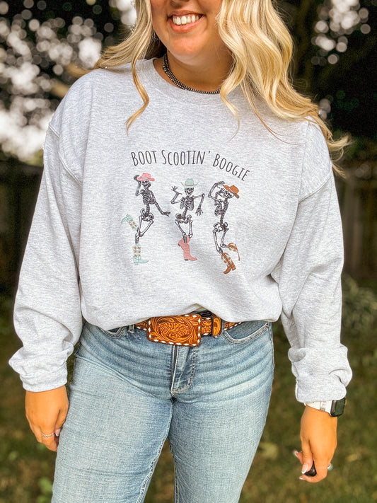 Fall western outfit with Skeleton Boot Scootin' Crewneck styled with jeans and leather belt, worn by smiling woman outdoors.
