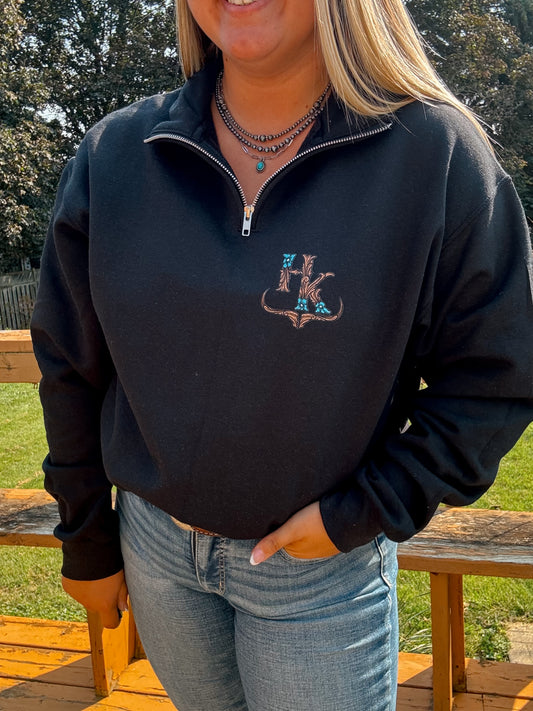 Close-up of the tooled turquoise logo embroidery on black quarter zip – textured western branding from Hides and Kinds.