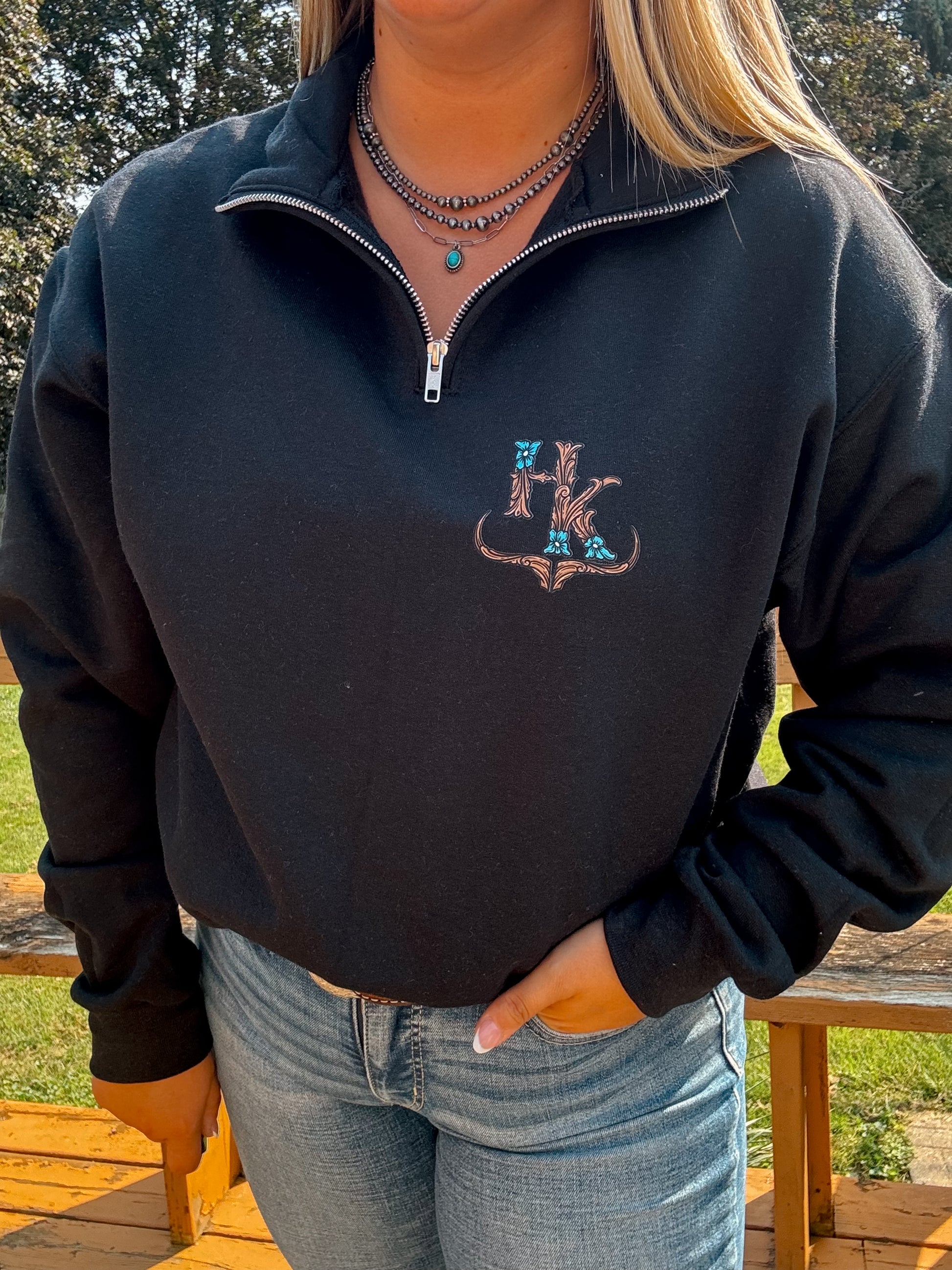 Black western quarter zip with turquoise tooled-style Hides and Kinds logo on left chest – styled casually with jeans.