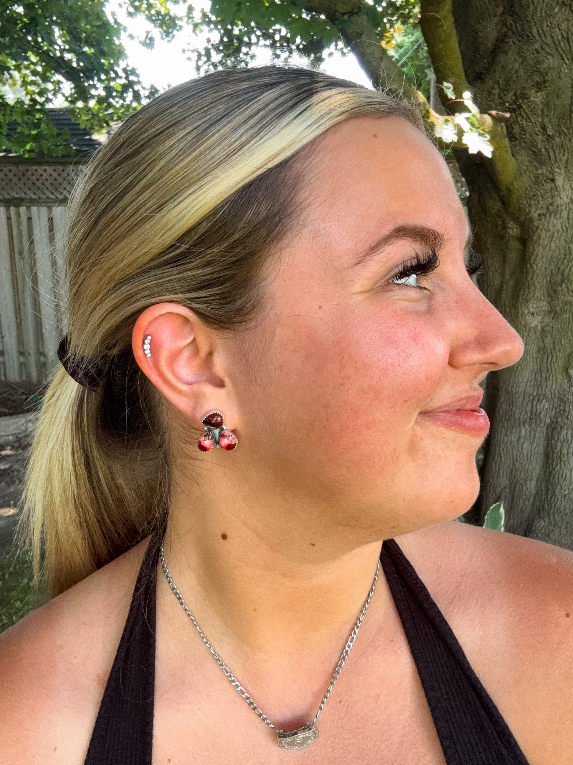 Dahlia Rose Triple Stone Stud Earrings in natural light with greenery background