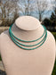 Close-up of layered Turquoise Sierra Necklace displayed on beige jewelry stand outdoors.