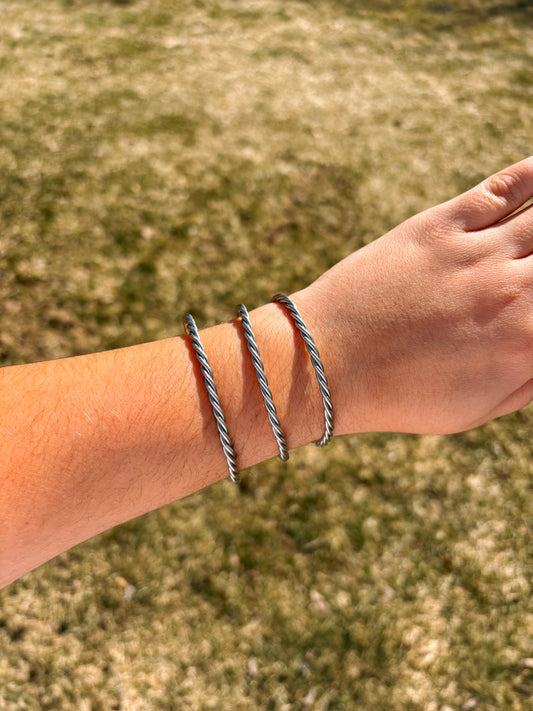 Western style twisted rope cuff bracelet stacked on wrist outdoors