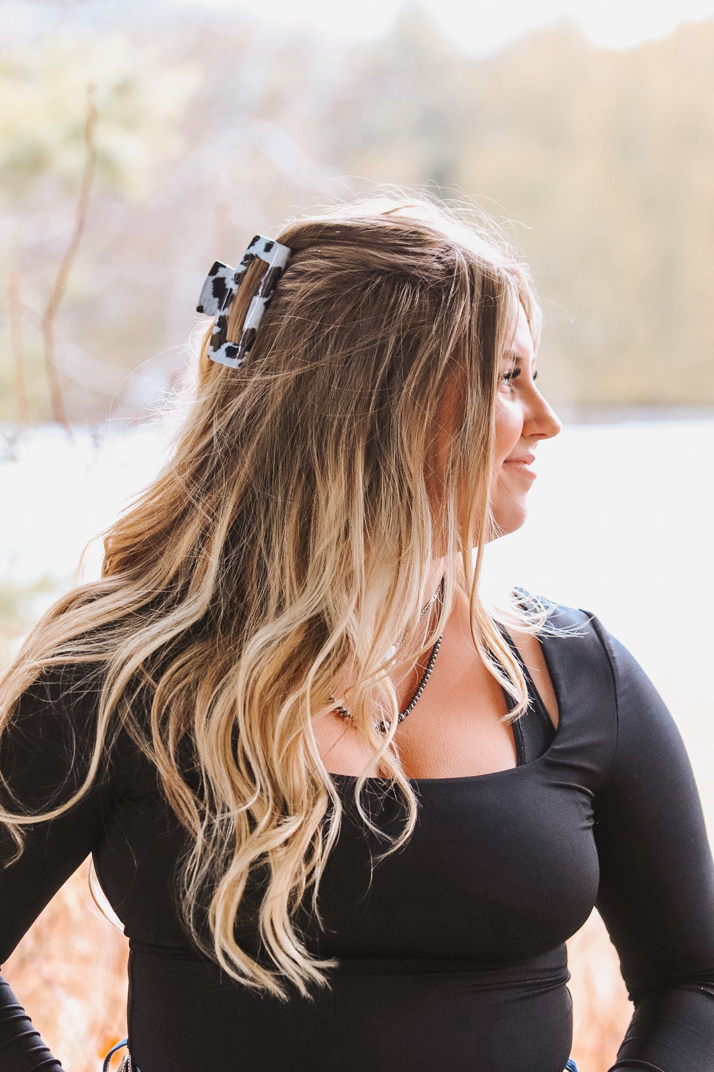 Western cow print claw clip in black and white pattern securing half-up hairstyle