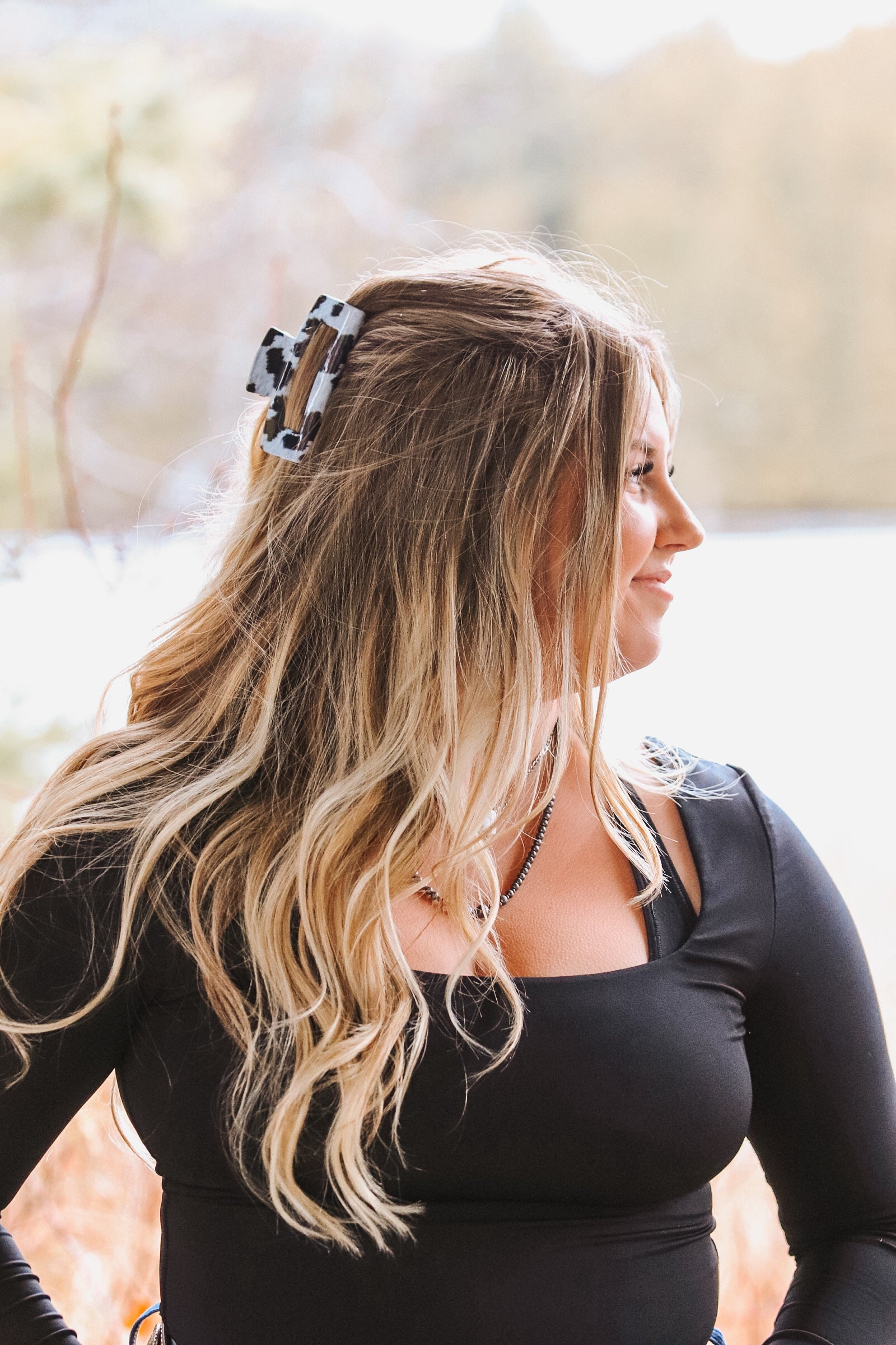 Western cow print claw clip in black and white pattern securing half-up hairstyle