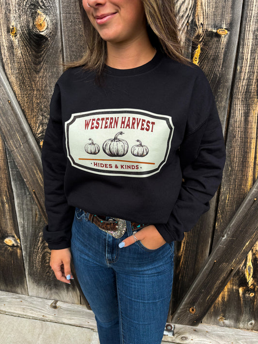 Side angle of Western Harvest crewneck showing rustic pumpkin patch design on black sweatshirt, styled with denim.