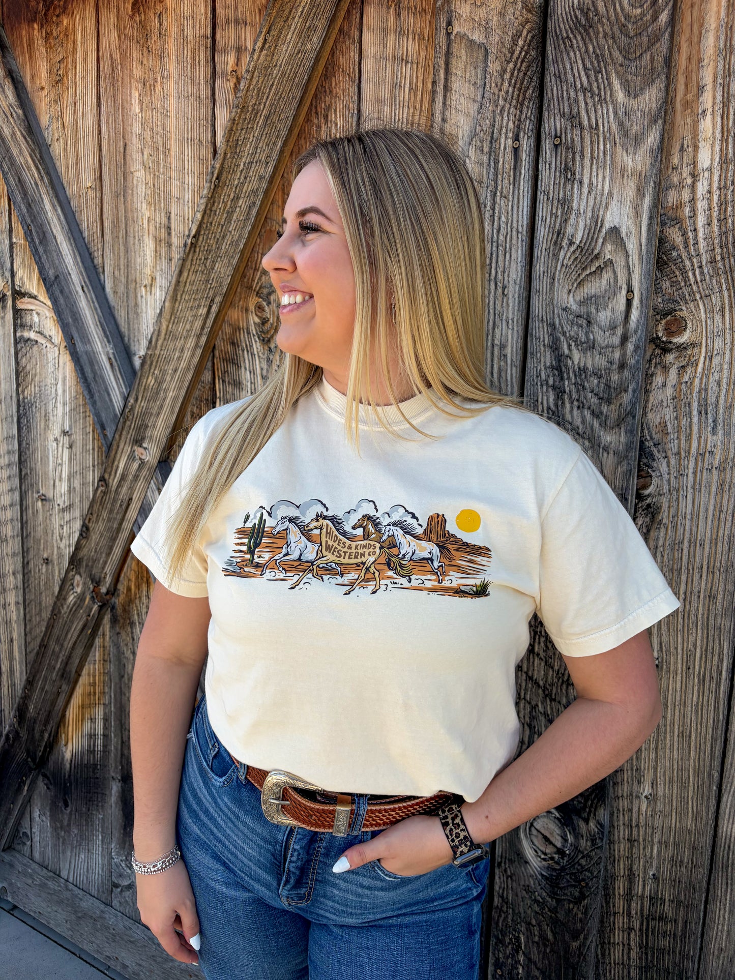 Woman wearing cream Wild Run Tee styled with jeans and belt western outfit