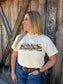 Woman wearing cream Wild Run Tee styled with jeans and belt western outfit