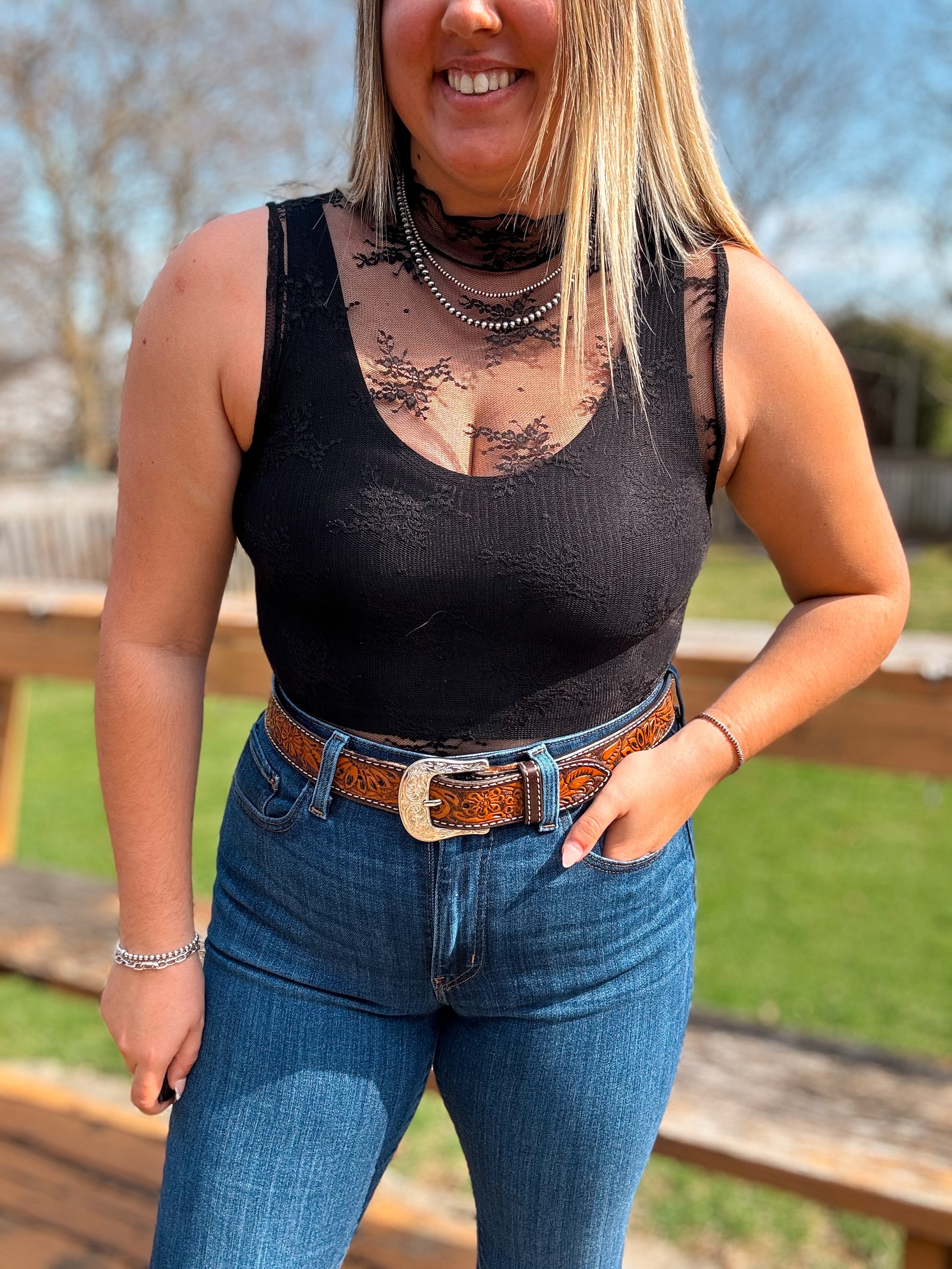 Close-up of black lace mesh tank top with sheer neckline and layered necklaces